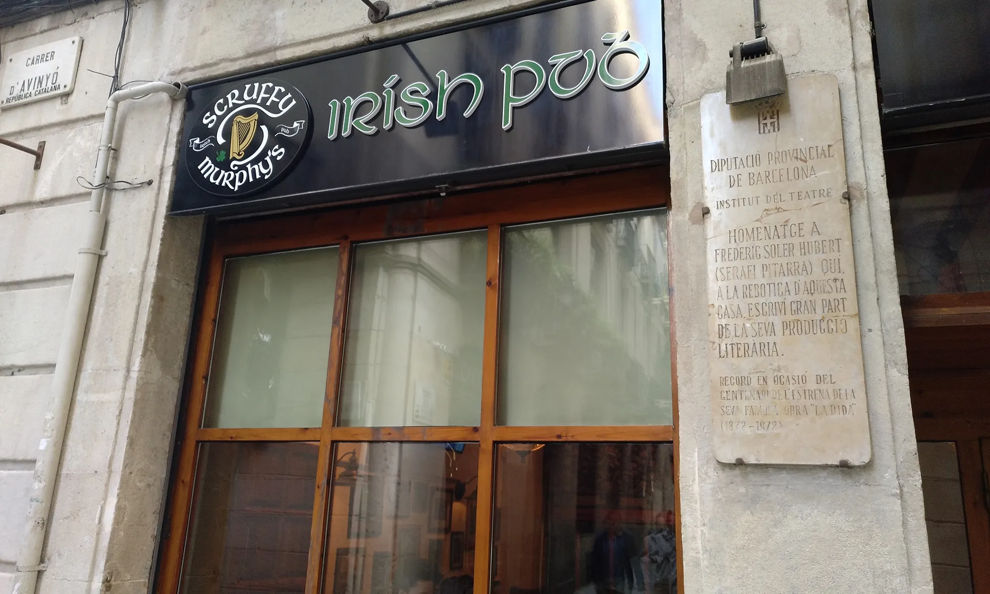 Una placa de la Diputació commemorant el centenari d'una obra de Pitarra, conviu amb aquesta nova realitat, totalment aliena a la seva naturalesa