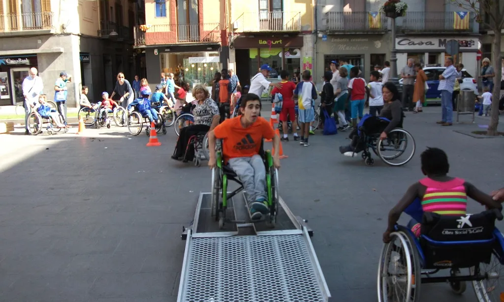 Acció de sensibilització on joves fan slaloms amb cadires de rodes.