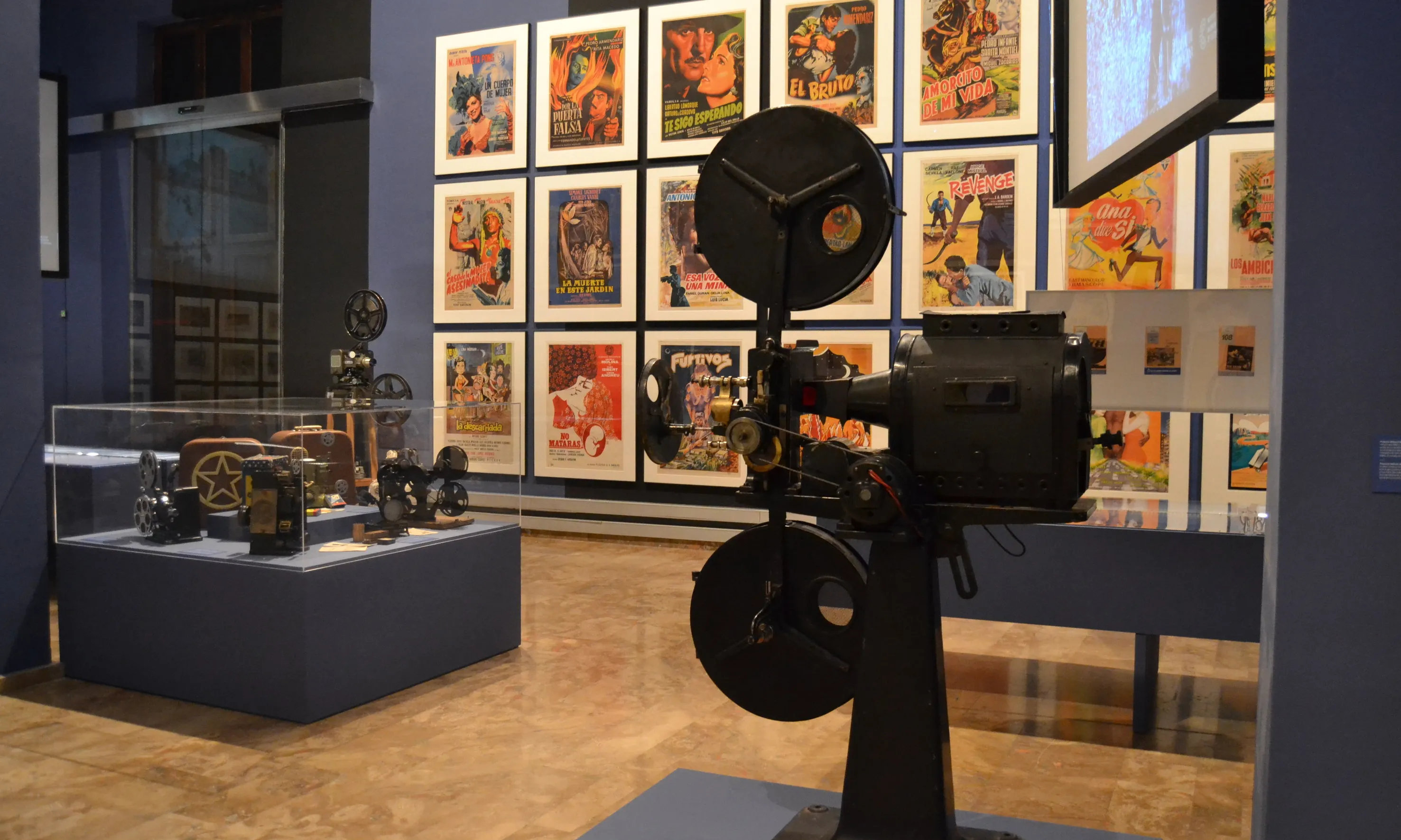 Exposició de cinema amb cartells de películes i un projector antic.