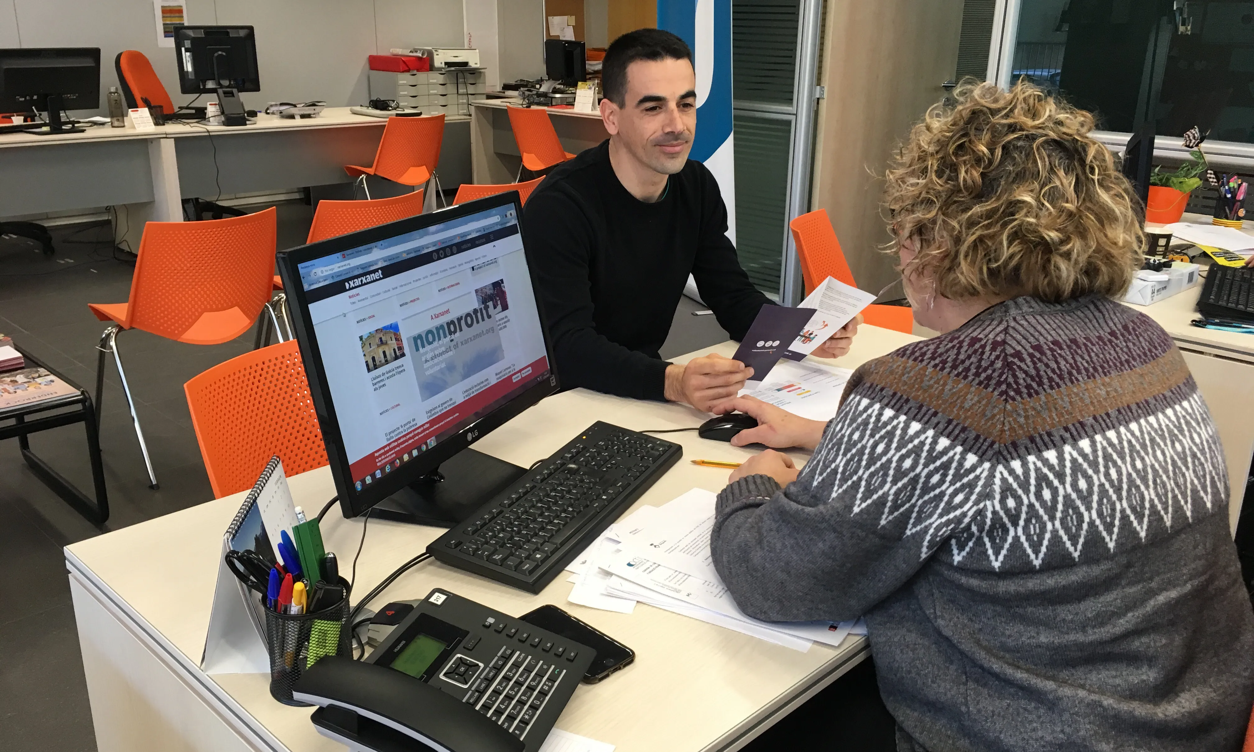 Noi i nois a una banda i altra de la taula en el Punt de Voluntariat del Berguedà