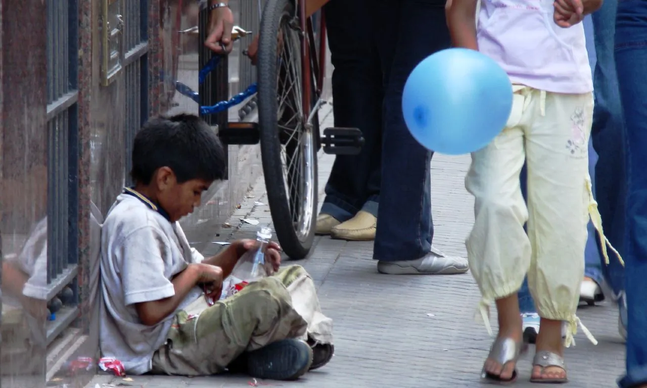 Nen assegut al carrer veient passar un globus