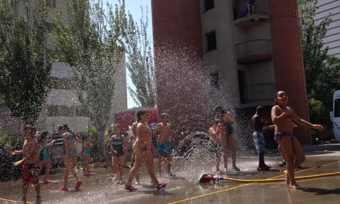 Nenes i nens jugant amb jocs d'aigua en una plaça