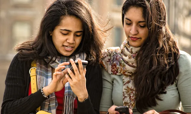 Fotografia de dos noies utilitzant un telèfon mòbil