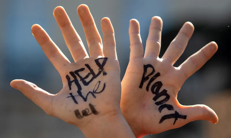 Dues mans creuades amb "Help the Planet" pintat