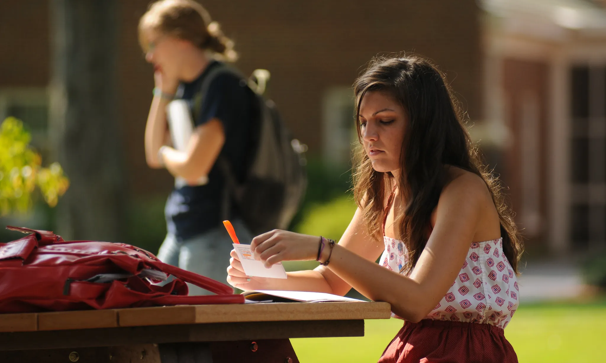 Noia estudiant en un banc