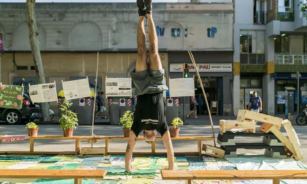Jove fent equilibris en una plaça del pàrquing al barri de Sant Antoni durant el Park(ing) Day.