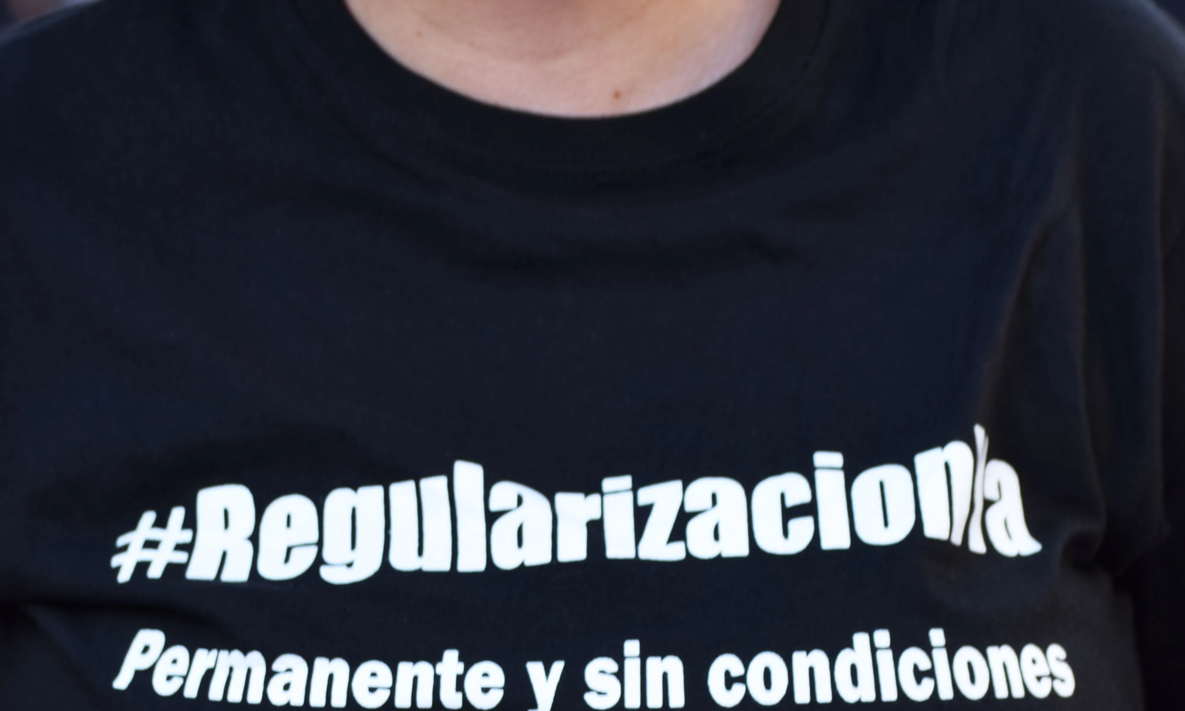 Una persona amb una samarreta que reclama la regularització de les persones en situació administrativa irregular.