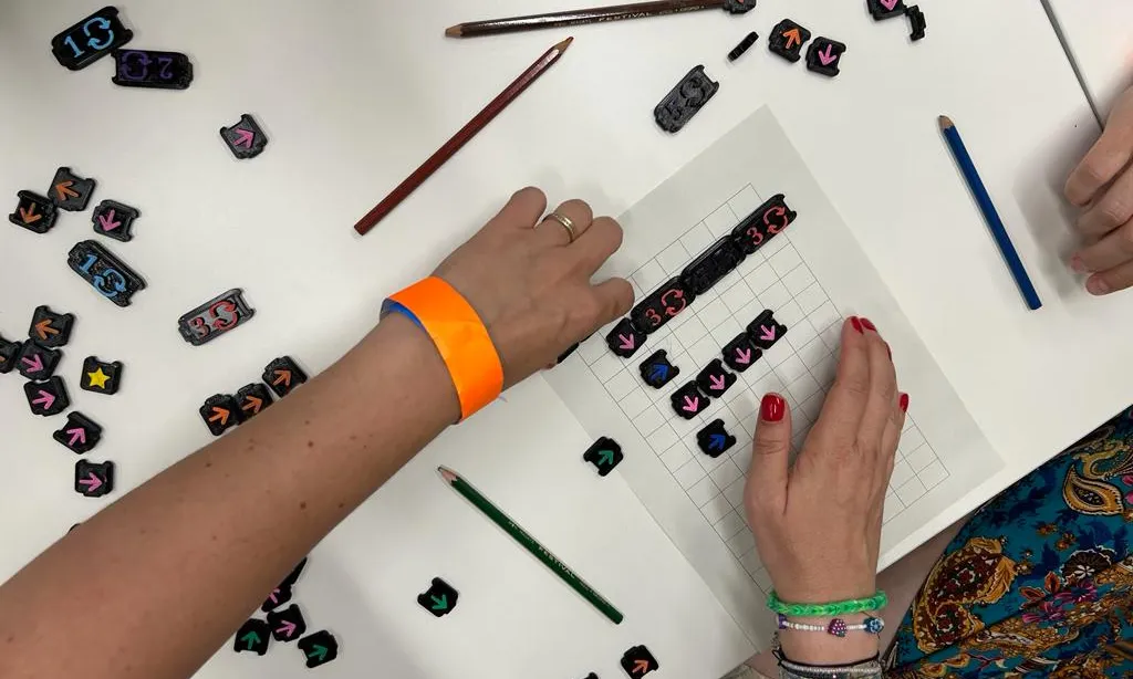 Les participants en el taller de jocs desconnectats fent la segona dinàmica, el joc de programació amb fitxes. Font: Coletic.