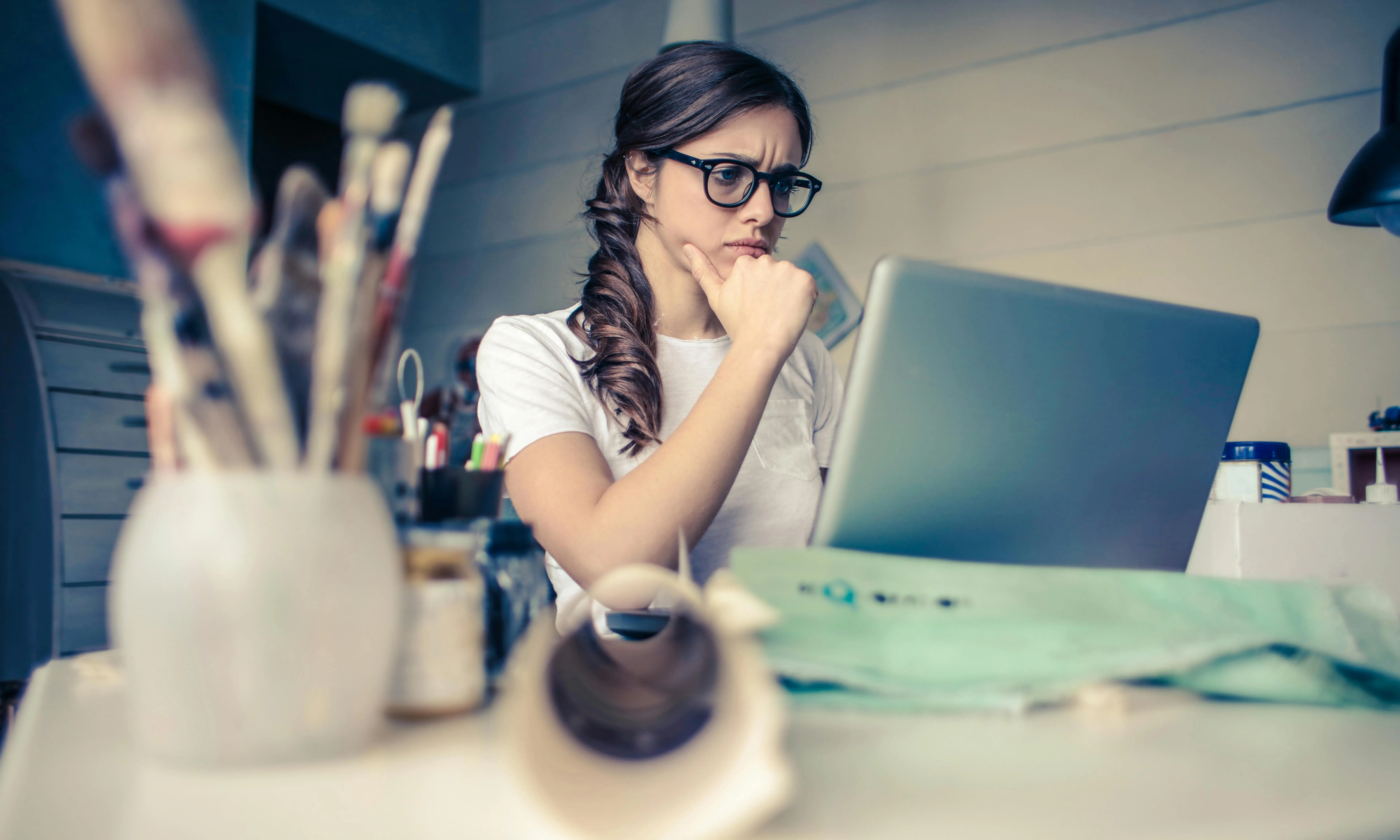 Noia amb estris de pintura mirant un ordinador. Font: Pexels - Andrea Piacquadio