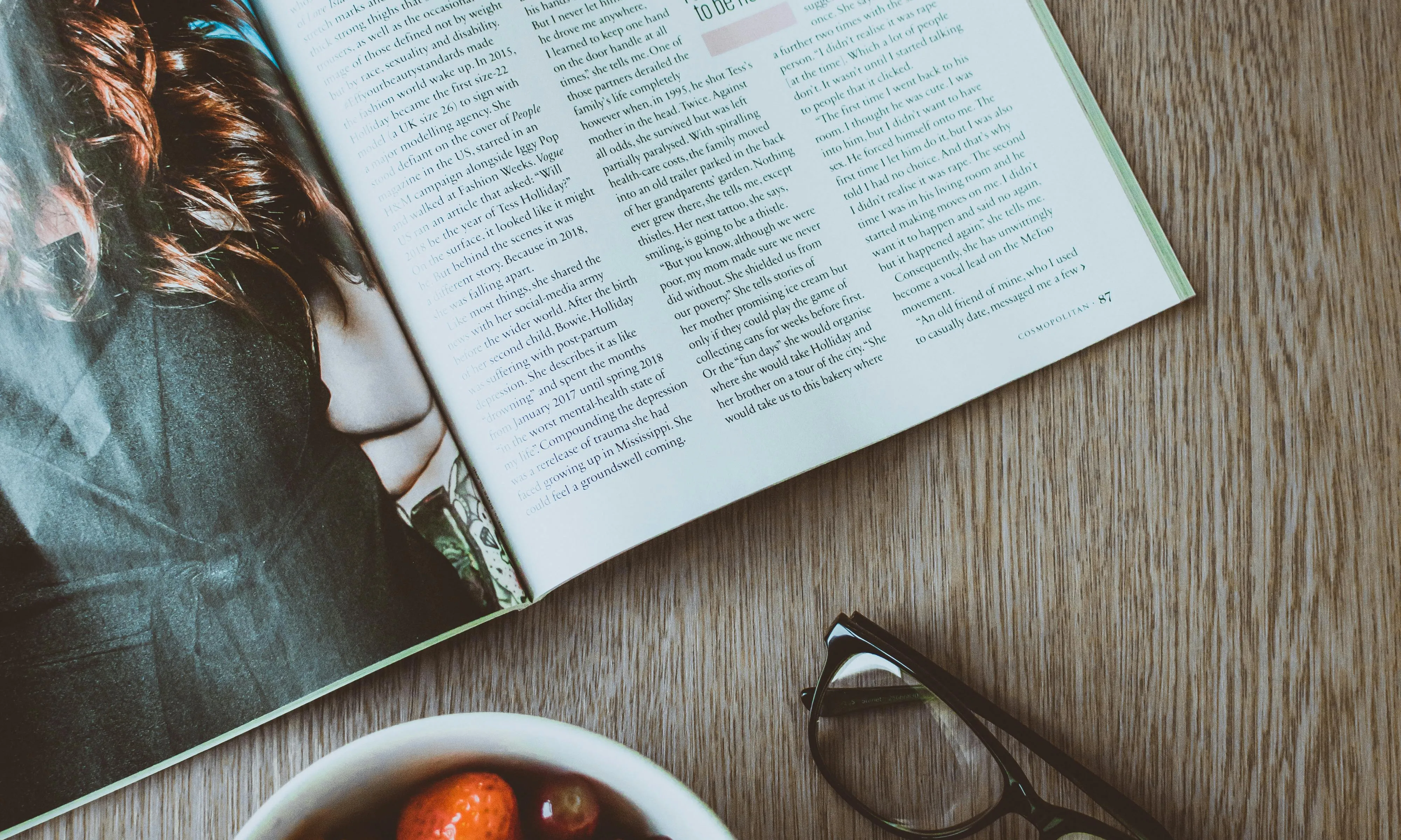Taula amb una revista, unes ulleres i un bol amb menjar