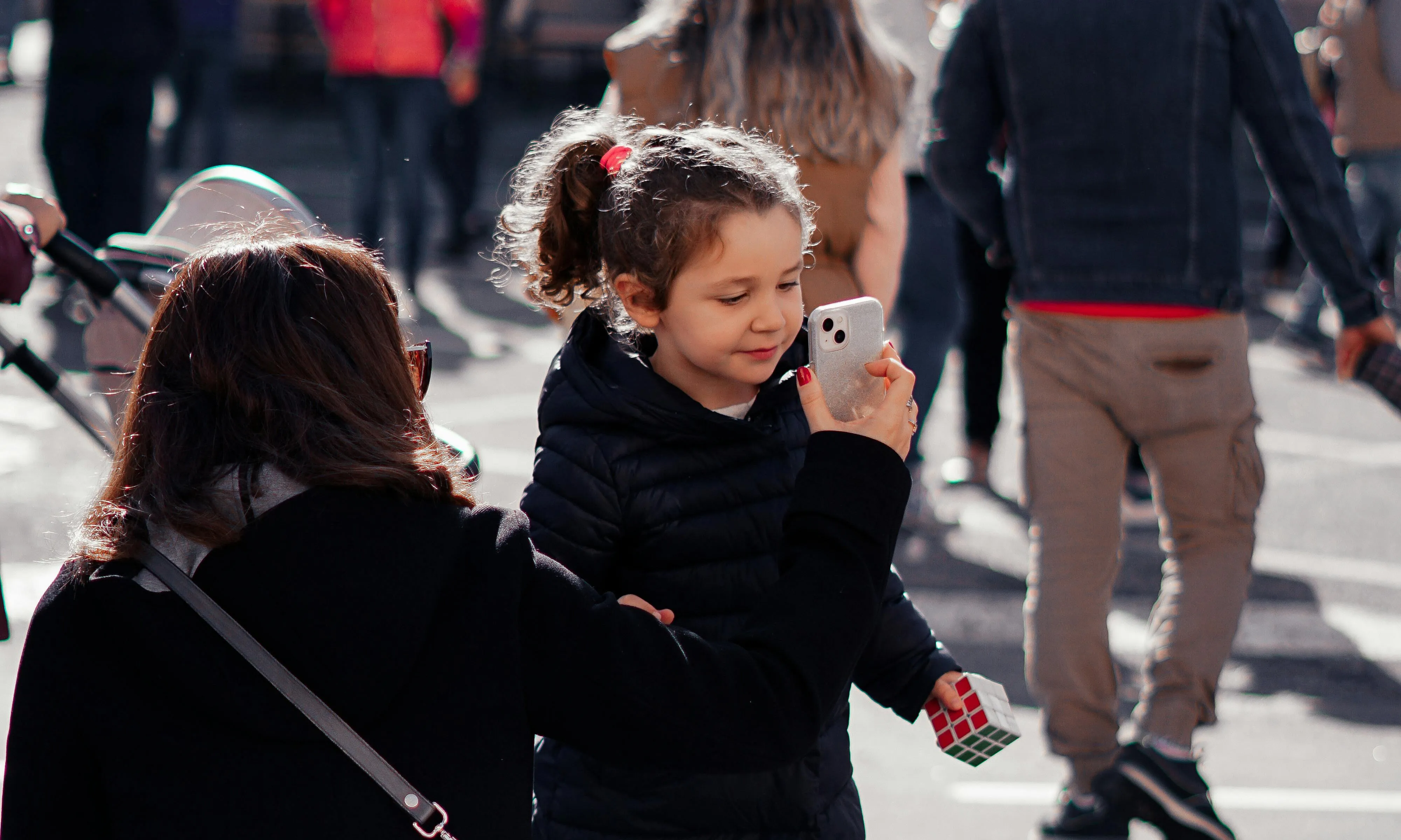 Nena mirant el mòbil que li ensenya un adult. Font: Pexels - Hardial Singh