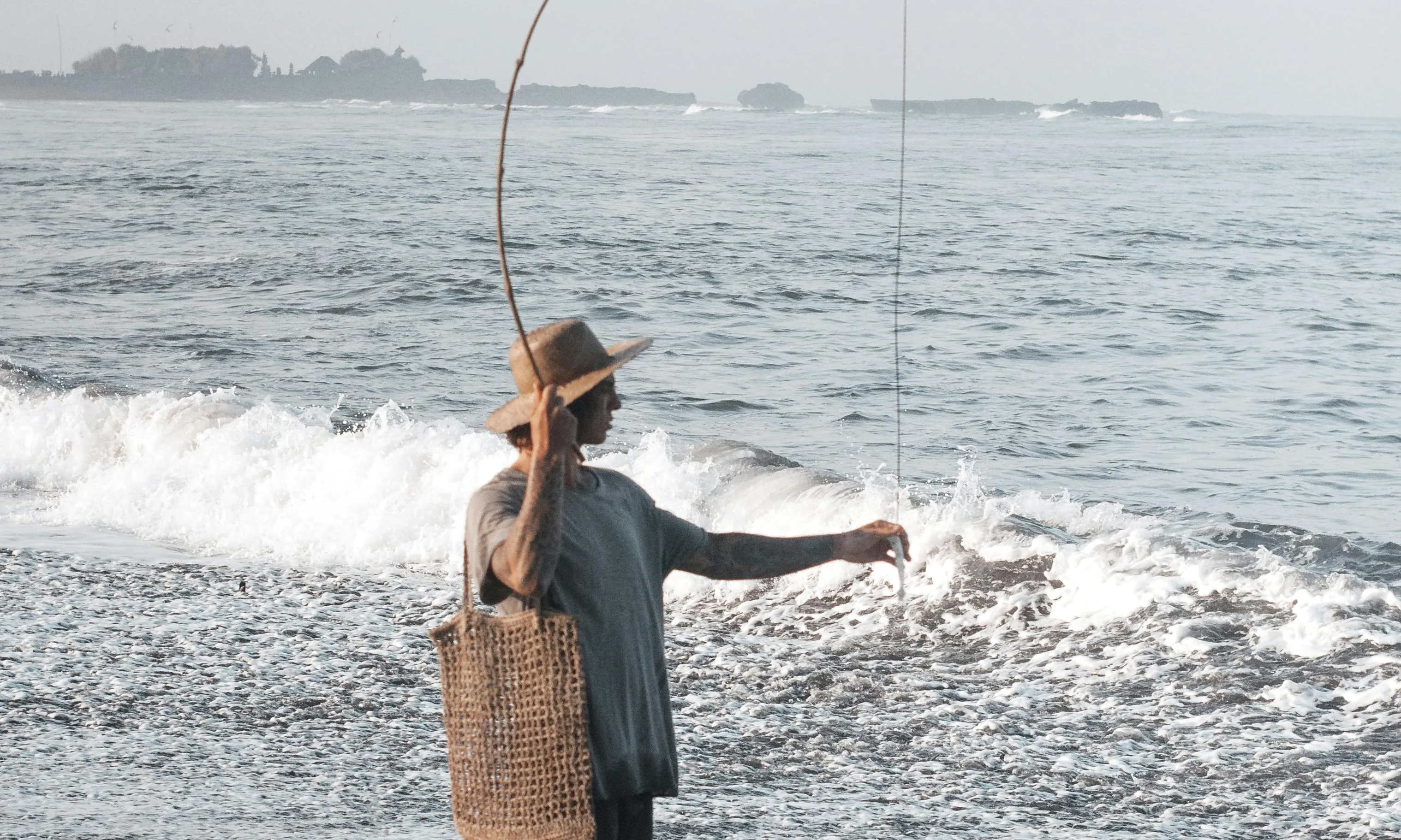 Noia pescant a la platja. Font: Pexels - ROMAN ODINTSOV