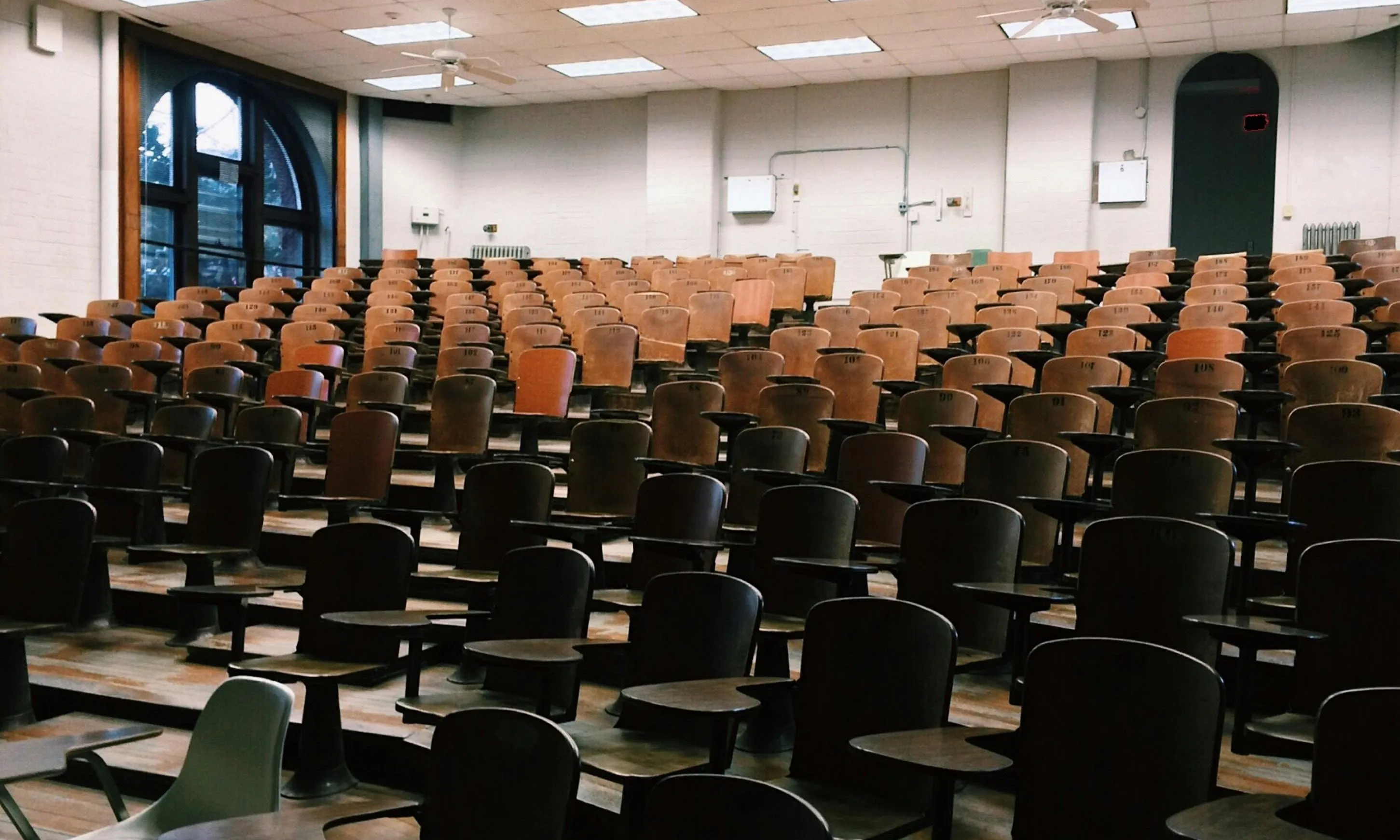 Aula universitària amb cadires de fusta tipus amfiteatre buida