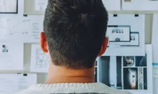 Home observant una paret on hi pengen fulles amb dades i idees