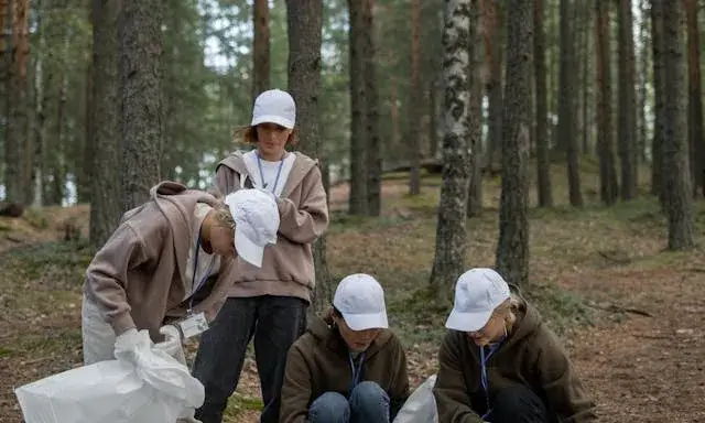 Persones voluntàries recollint brossa en el bosc