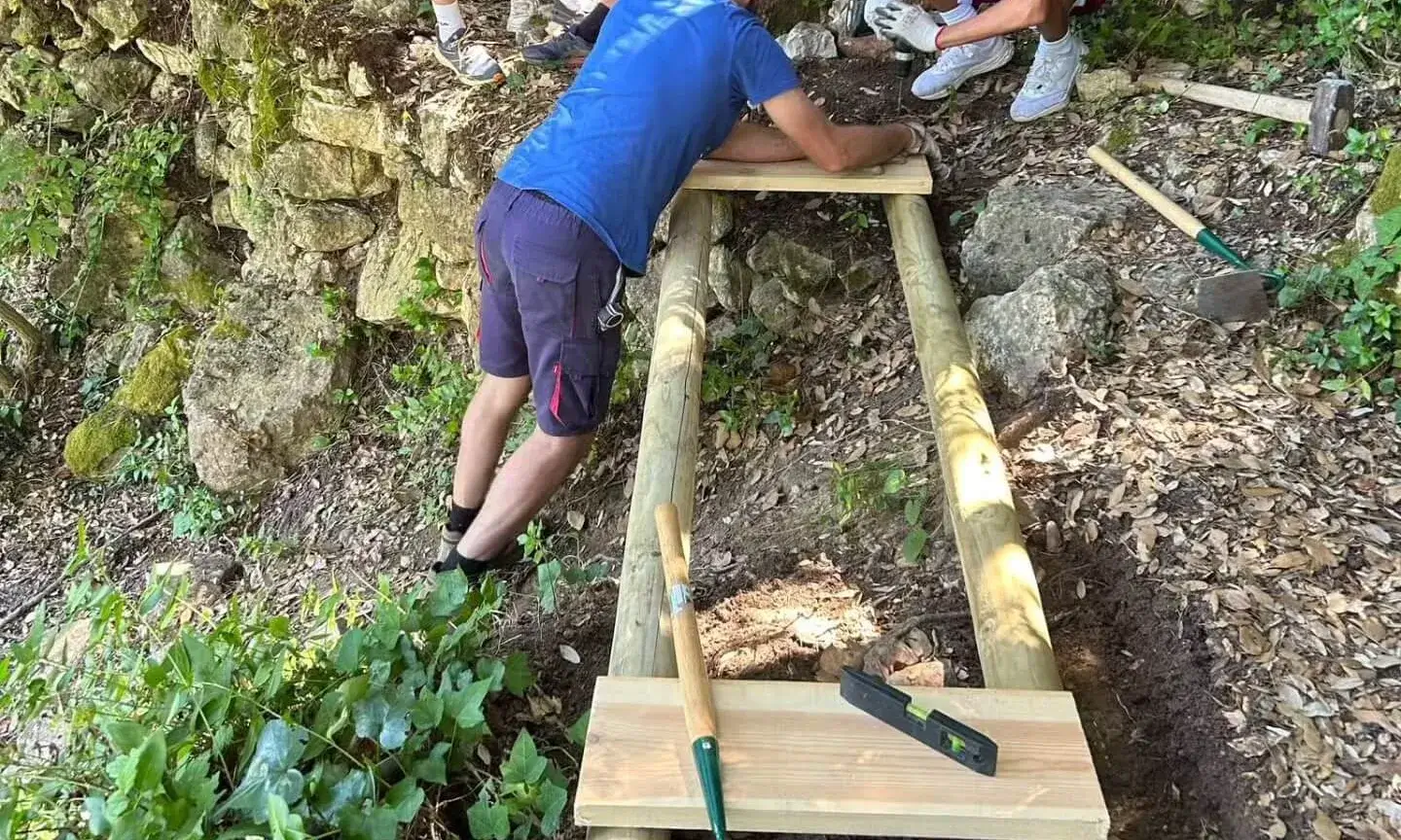 Grup de joves reconstruint una pasarel·la de fusta