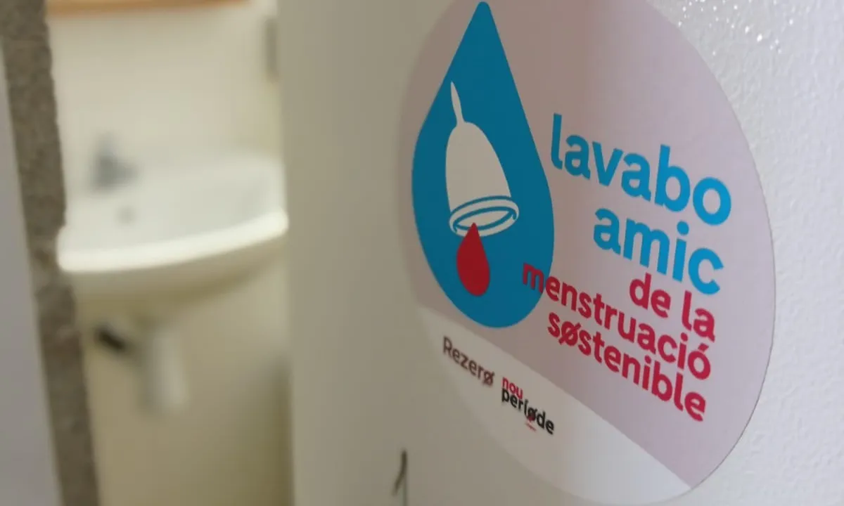 Cartell a la porta d'un lavabo on es llegeix 'Lavabo amic de la menstruació sostenible'