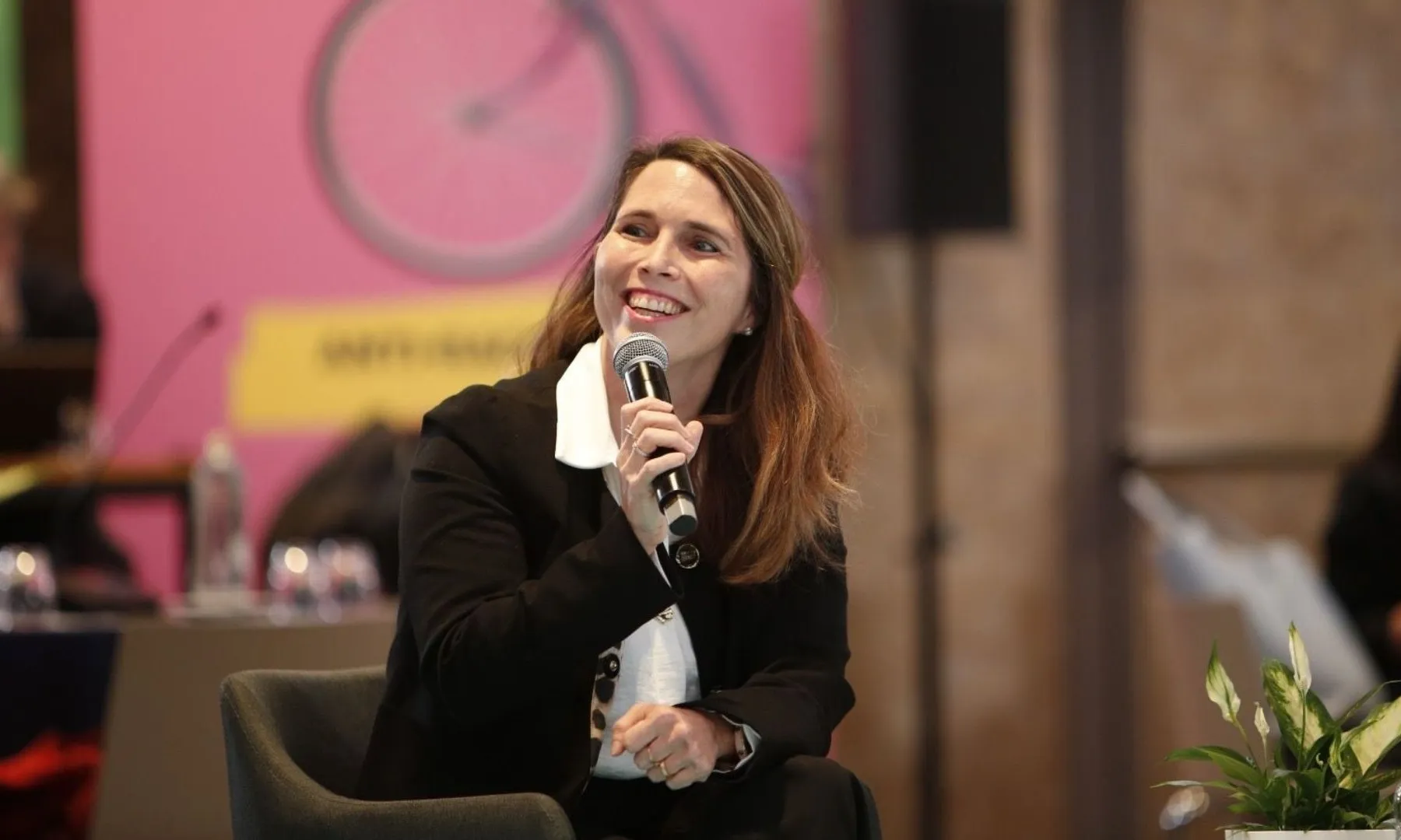Marta Junqué parla amb un micròfon en un acte públic sobre usos del temps davant d’un públic assistent.