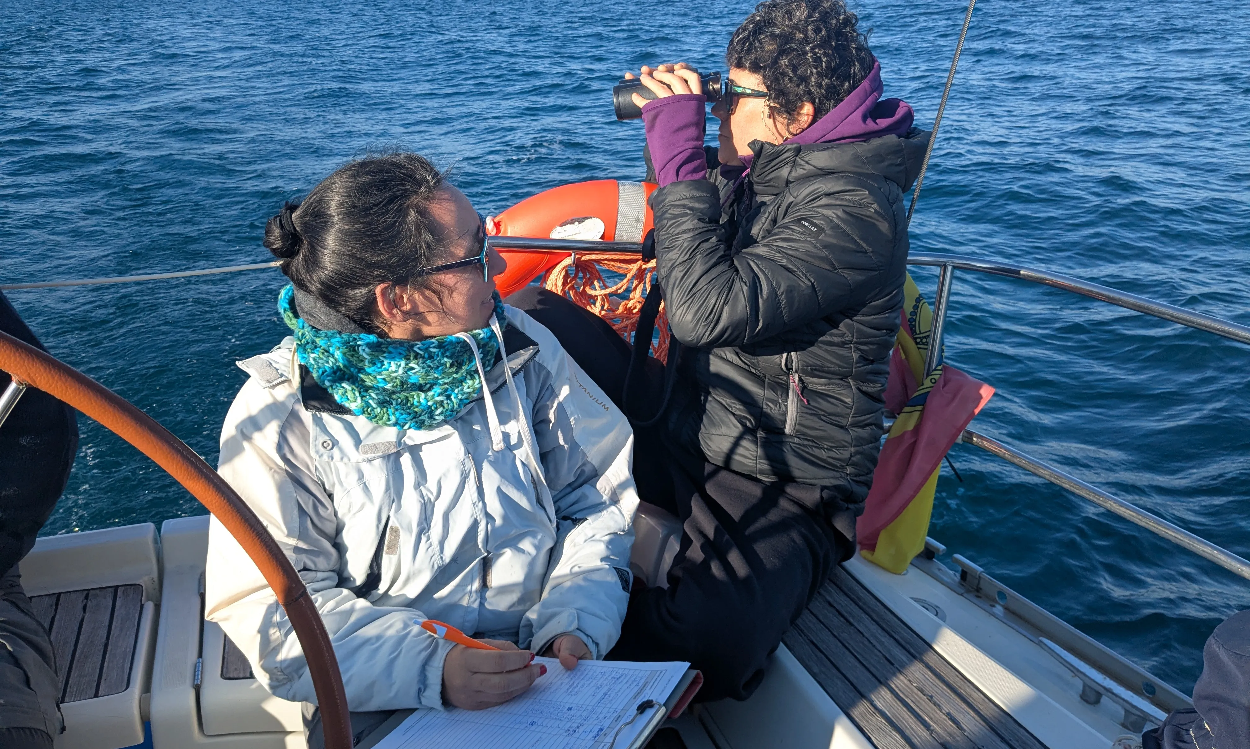 Dues voluntàries en un vaixell al mar, mirant per uns binocles.