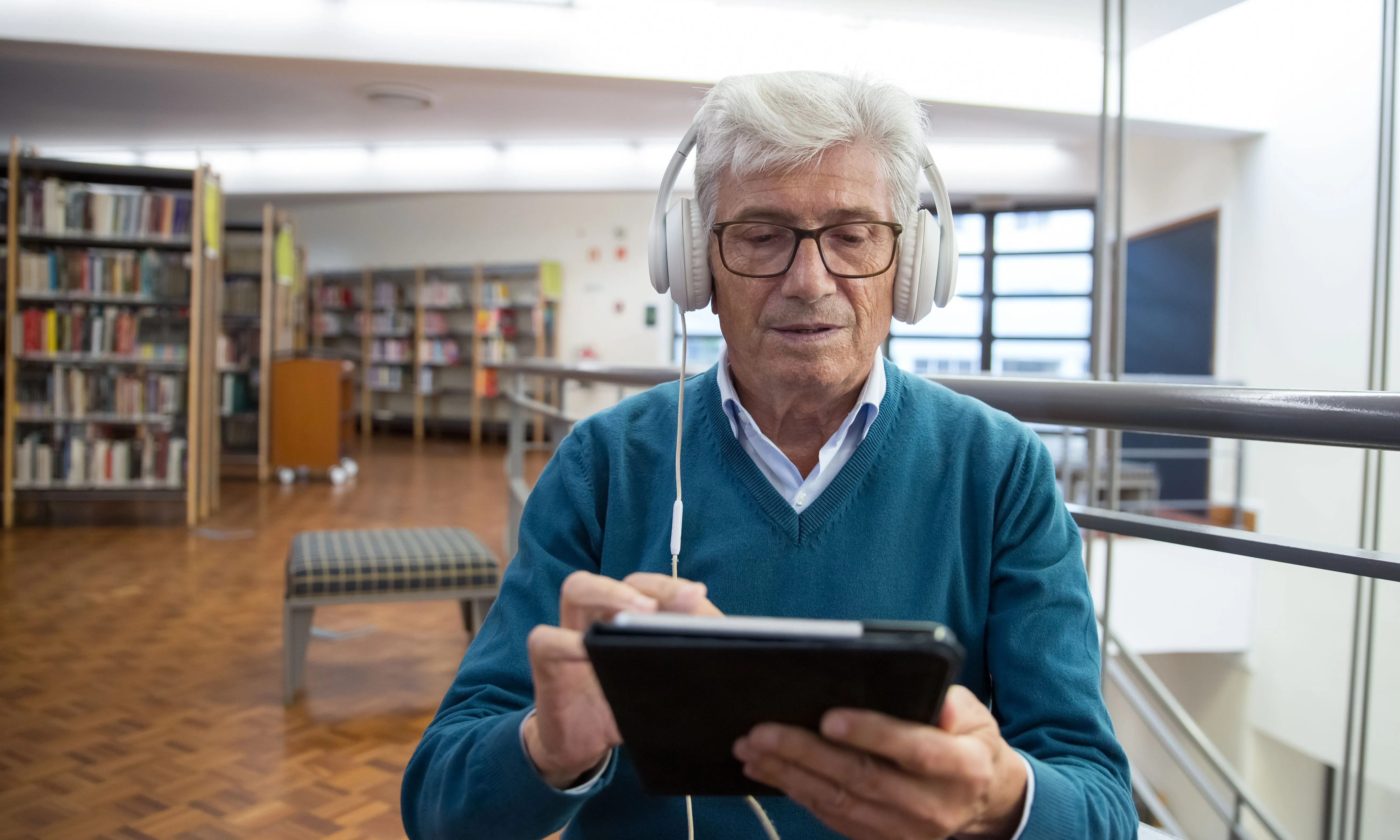 Persona escoltant un audiollibre amb auriculars i un dispositiu electrònic.