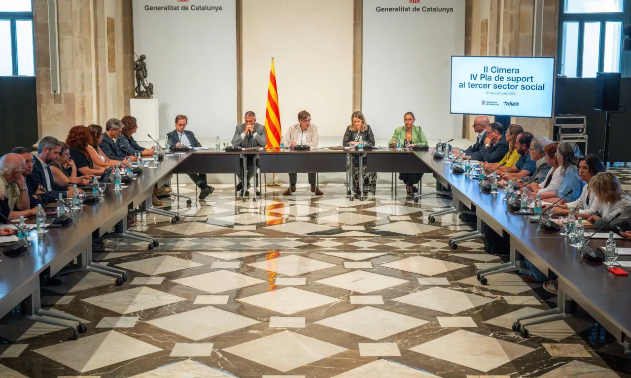 Salvador Illa, acompanyat dels consellers i representants del Tercer Sector, en una taula en forma de cercle.