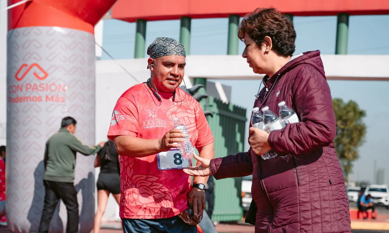 Un corredor adult rep aigua a la línia de meta d'una marató d'una voluntària.