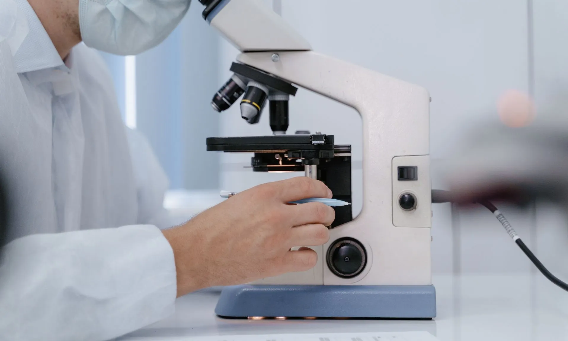 Investigador analitzant mostres amb un microscopi en un entorn de laboratori.