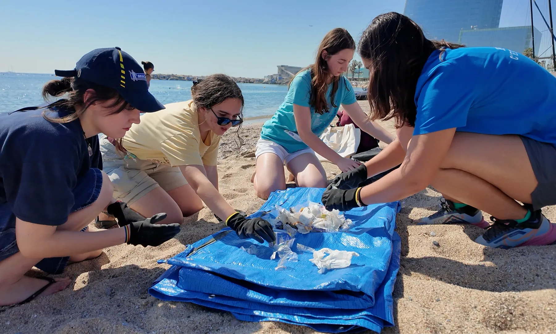Un grup de quatre noies classificant residus que han recollit a la platja.