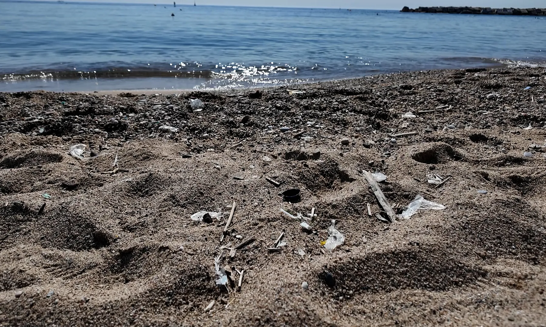 Imatge de la sorra de la platja plena de plàstic i residus.